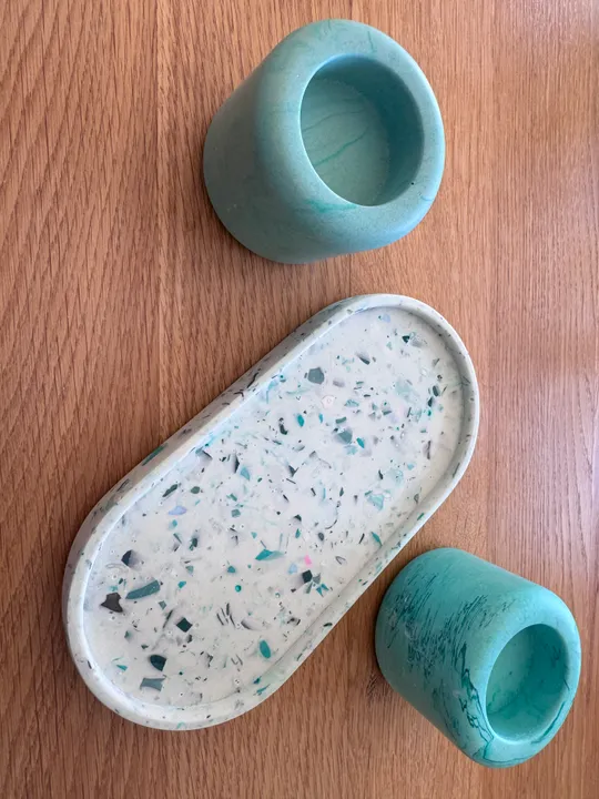 Two teal cups and terrazzo tray on table.