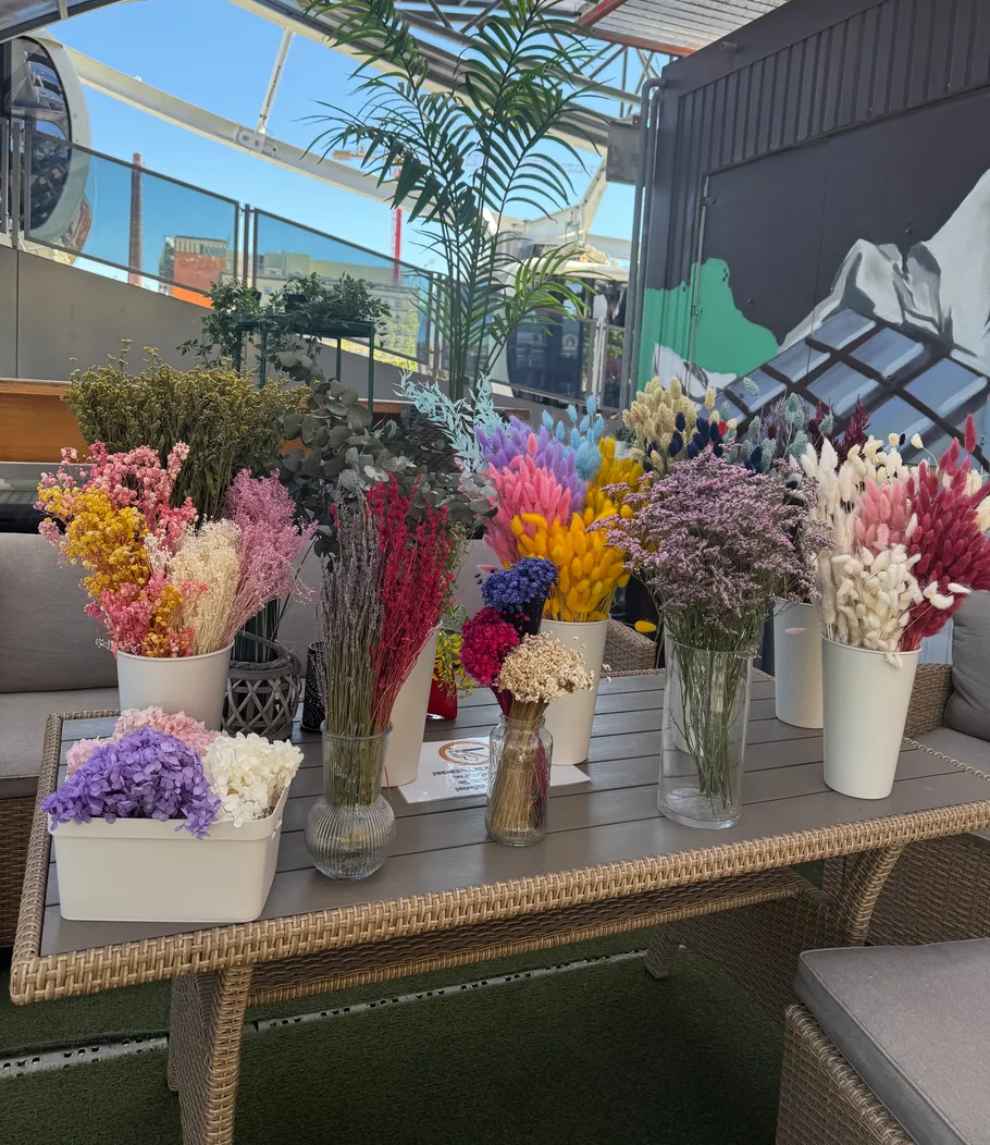 Bunte getrocknete Blumen auf einem Terrassentisch.