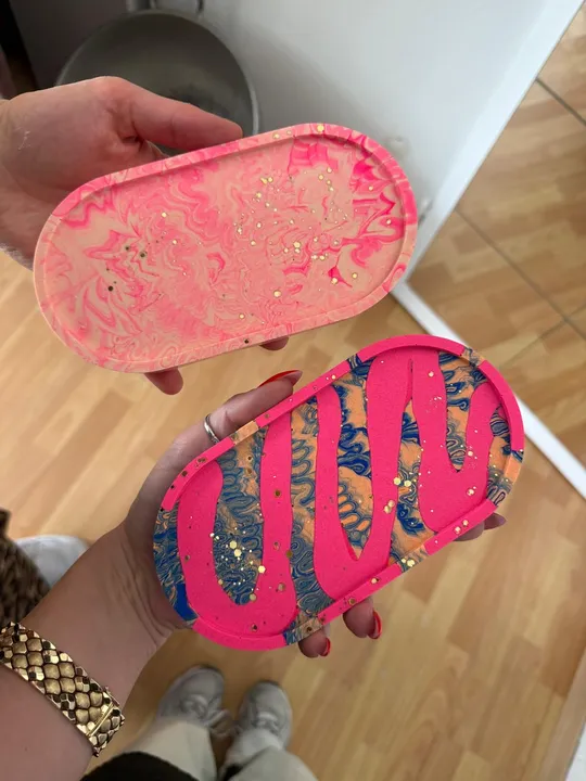 Two hands holding colorful resin trays.