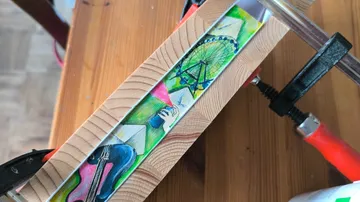Holzschraubzwinge sichert Kunstwerk auf Holztisch.