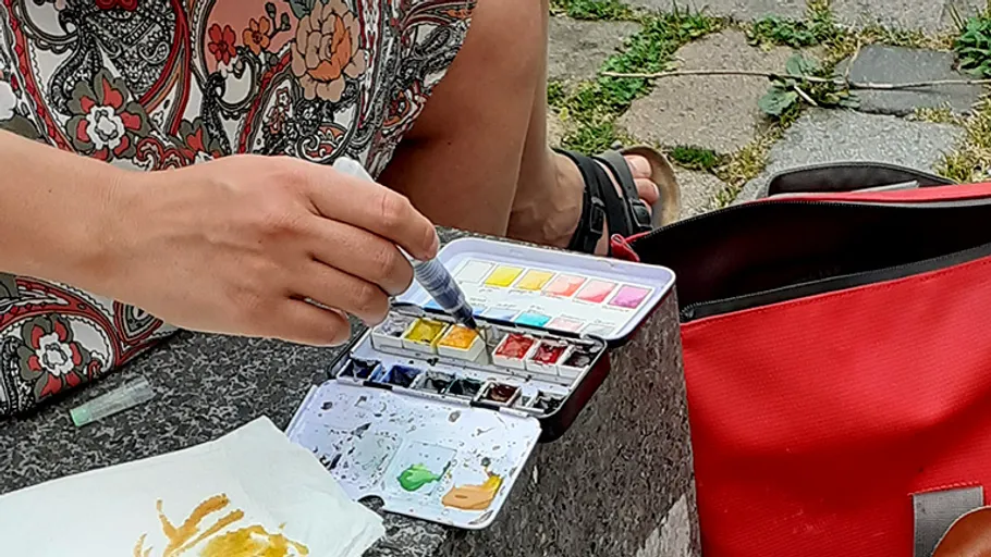 Person malt mit Aquarellen im Freien.
