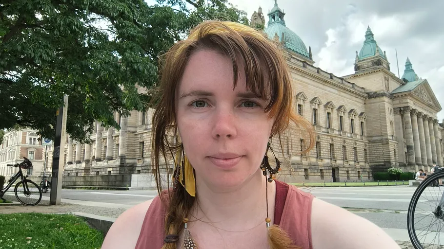Person sitting near historic building and trees.