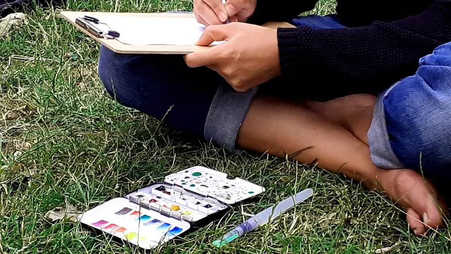Person painting outdoors on the grass.