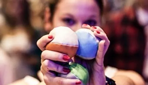 Person holding colorful juggling balls indoors.