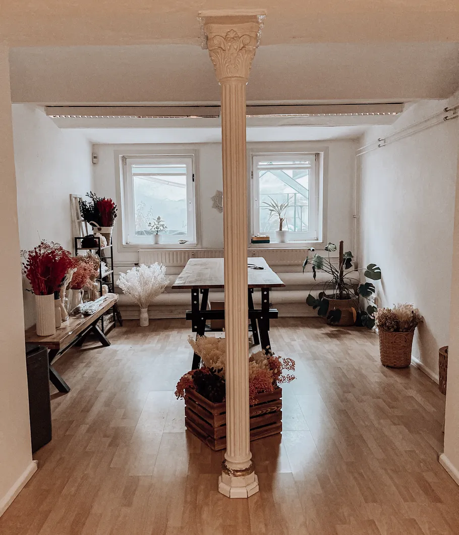 Säule teilt Raum mit Pflanzen und Tisch.
