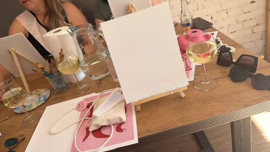 Tisch mit Kunstmaterialien und Weingläsern.