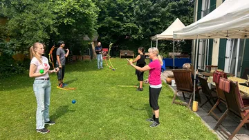 Personen üben Jonglieren im Garten.