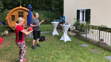 Zwei Personen jonglieren in einem Gartensetting.