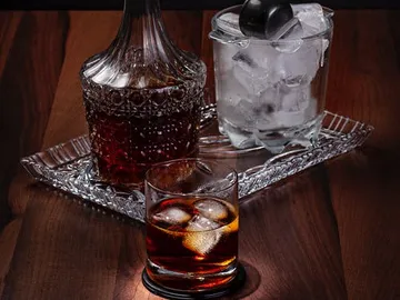 Eine Glasflasche und ein Glas mit Eis auf Holz.