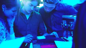 Personen untersuchen Objekte im blauen Licht.