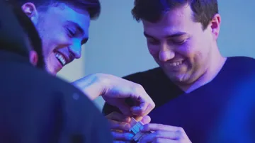 Zwei Männer lachen und lösen drinnen ein Puzzle.