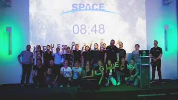 Gruppe posiert vor weltraumbezogenem Hintergrund.