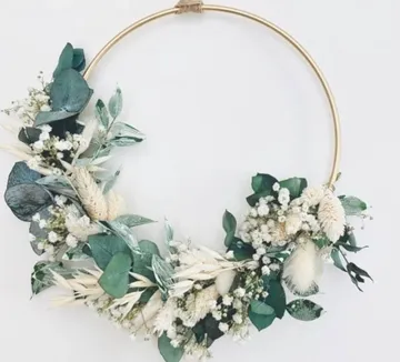 Blumenkranz mit Trockenblumen an Wand.