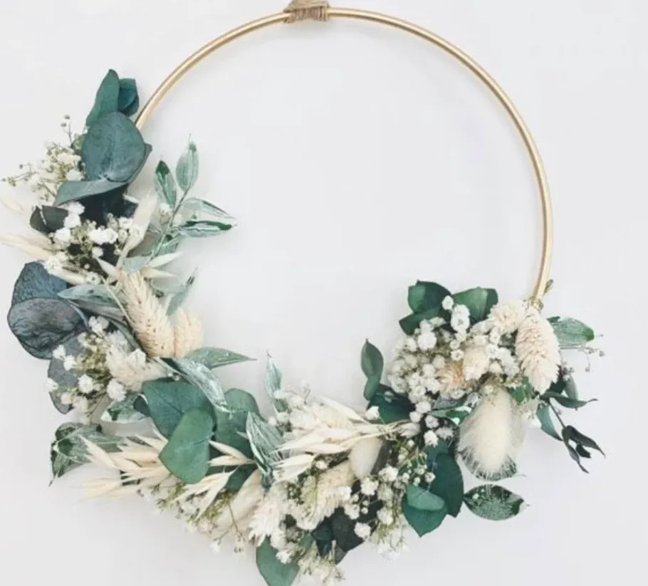 Blumenkranz mit Trockenblumen an Wand.