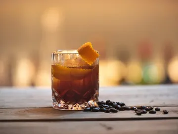 Ein Glas mit Getränk steht auf einem Holztisch.