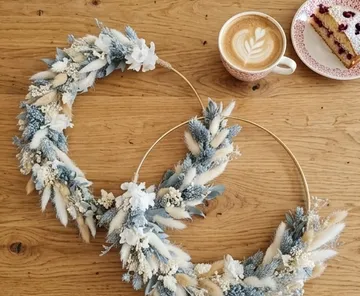 Zwei Blumenkränze auf Holztisch mit Kaffee.