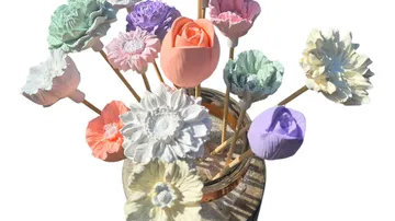 Bunte Tonblumen in einem Glas auf weißem Hintergrund.