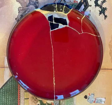 Red plate repaired with golden cracks.