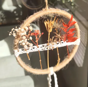 Getrocknete Blumen hängen in einem Jutekreis.