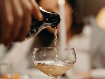 A bottle pours sparkling drink into a glass.