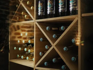 Bottles are stored on a wooden rack with a dark red background.