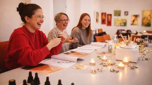 Three women laughing at a table with candles.