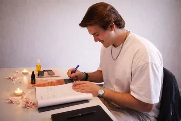 Mann schreibt an einem Tisch mit Kerzen.