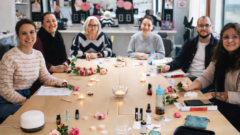 Gruppe am Tisch mit Blumen, lächelnd.