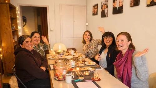 Fünf Frauen lächeln an einem Tisch.