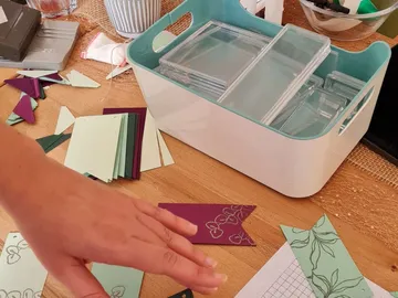 Hände sortieren bunte Papierstücke auf einem Tisch.