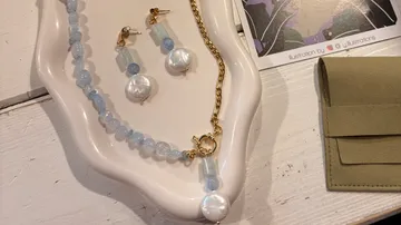 Schmuckset mit blauen Perlen auf weißem Teller.