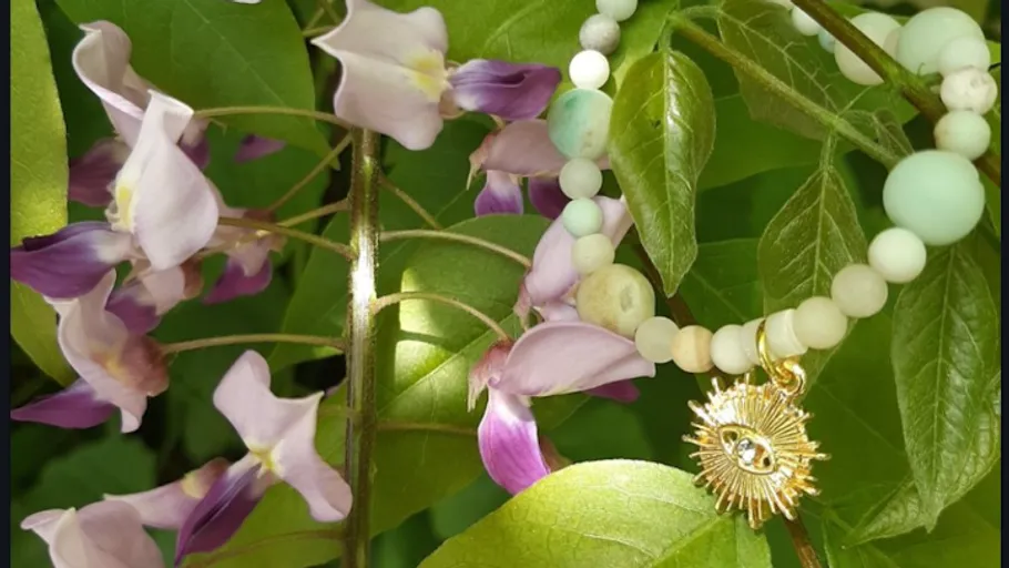 Bracelet and flowers among lush green leaves.