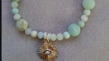 Perlenarmband mit Sonnenauge-Anhänger auf Stoff.