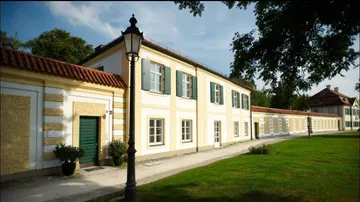 Yellow building with green shutters, sunny garden.