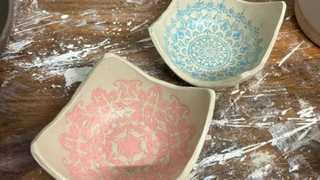 Two decorative bowls on a splattered table.