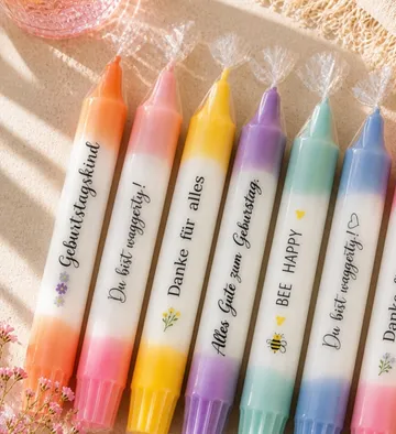 Colored candles with German text on table.