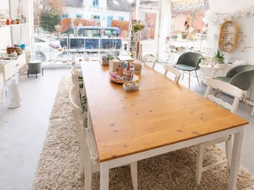 Long wooden table with art supplies near window.