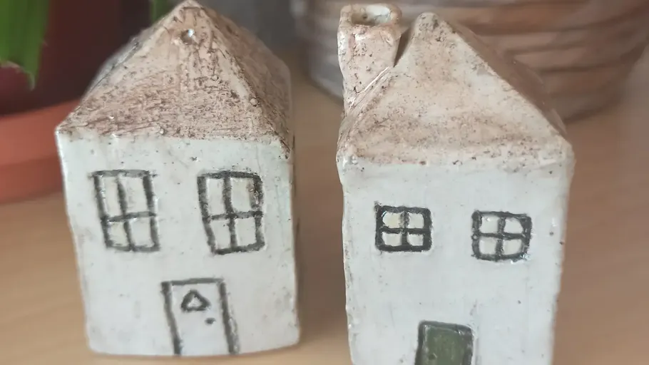 Two ceramic house figurines on wooden surface.