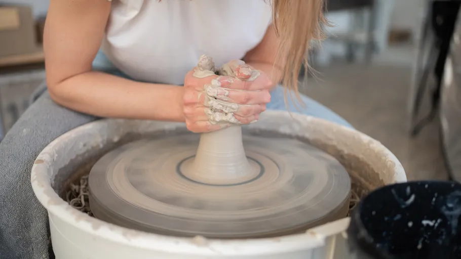 Person shaping clay on a potter's wheel.