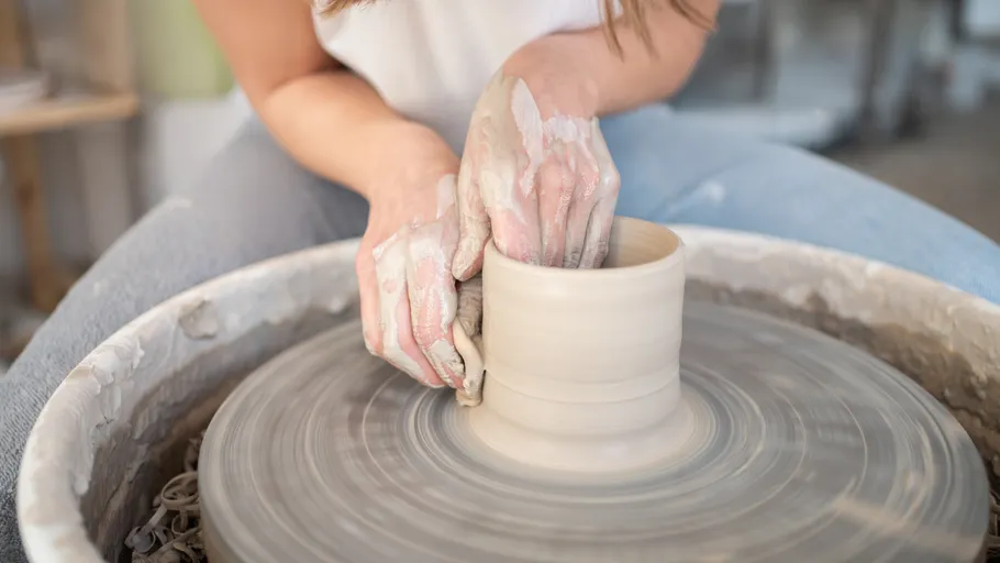 Person shaping clay on a pottery wheel.