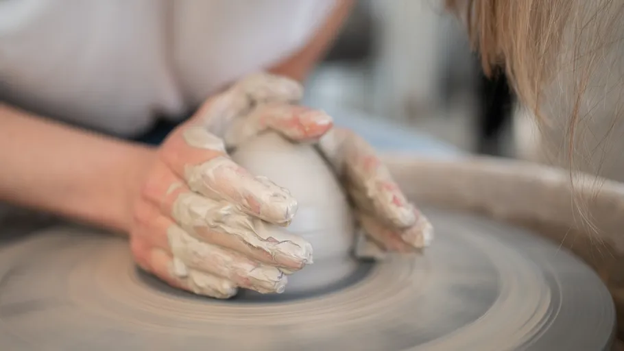 Hands shaping clay on a pottery wheel.