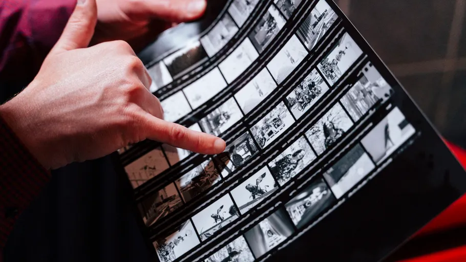 Hände halten ein Kontaktabzug von Fotos.