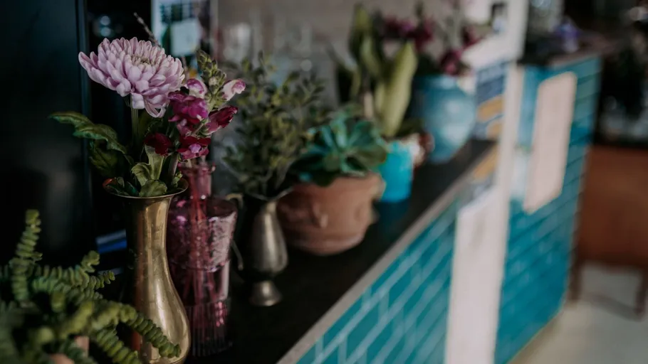 Vases with flowers on a turquoise tiled counter.