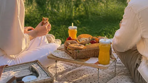 Two people enjoying picnic with snacks and juice.