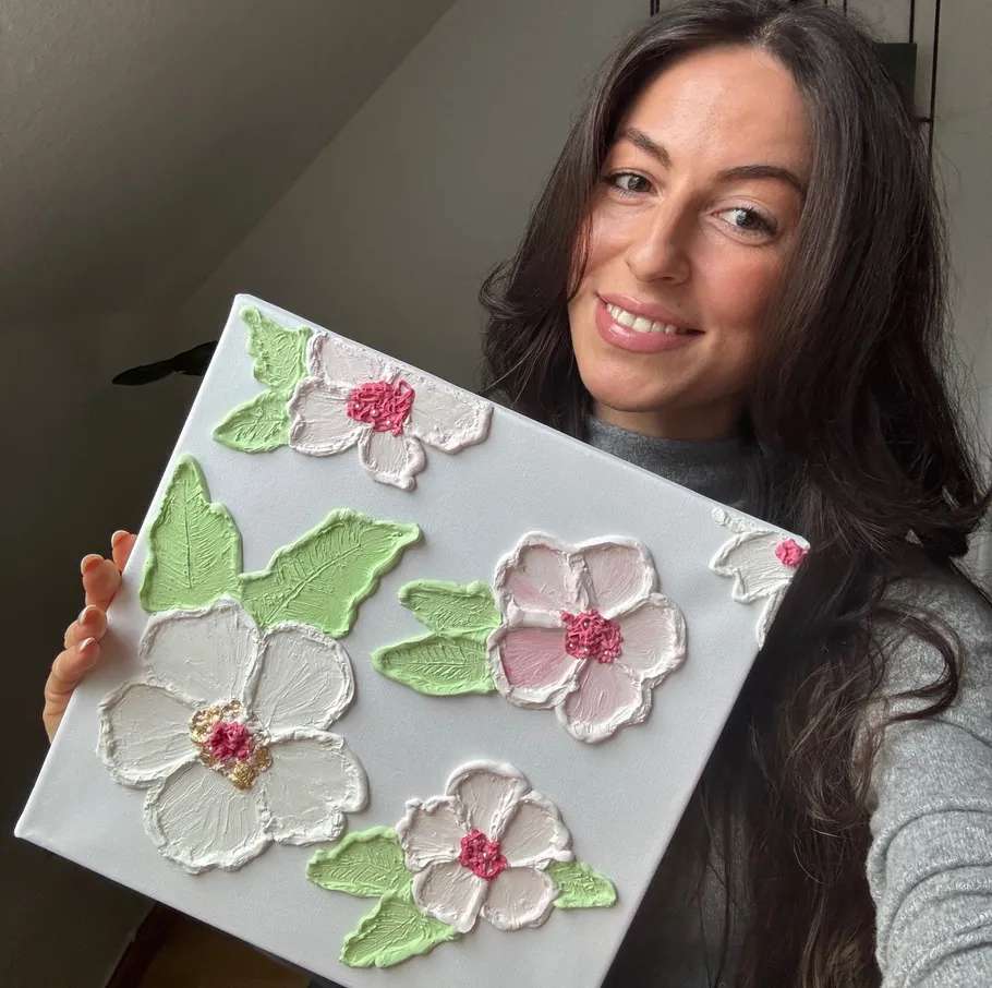 Woman holding floral textured artwork indoors.