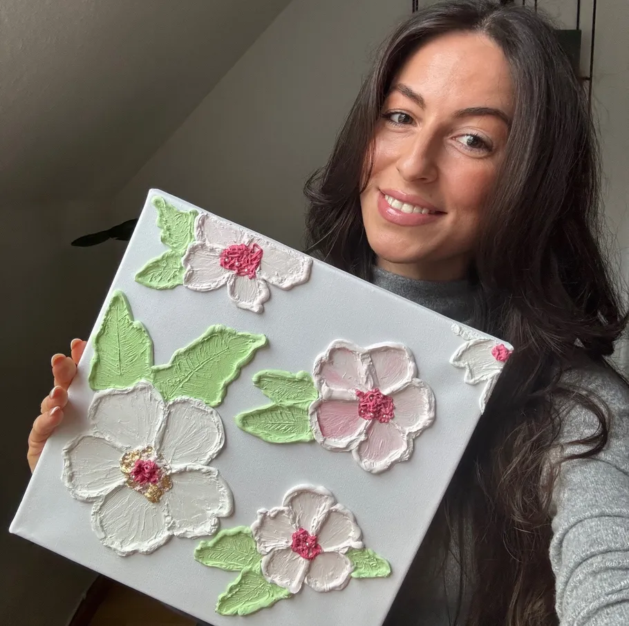 Woman holding canvas with textured flowers.