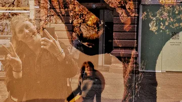 Reflection of woman posing in city window.