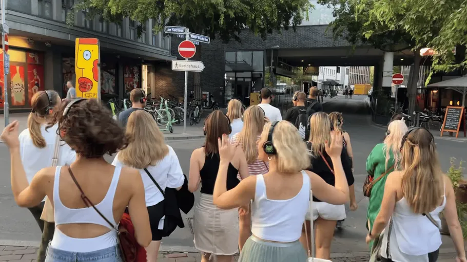 Gruppe mit Kopfhörern spaziert in der Stadtstraße.