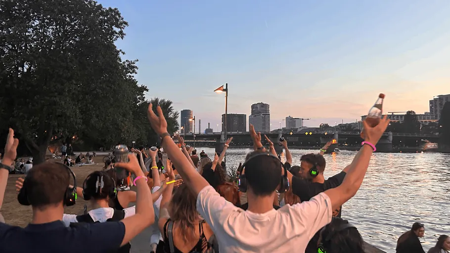 Menschen mit Kopfhörern tanzen am Fluss.