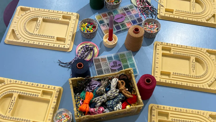 Beading supplies arranged on blue table.